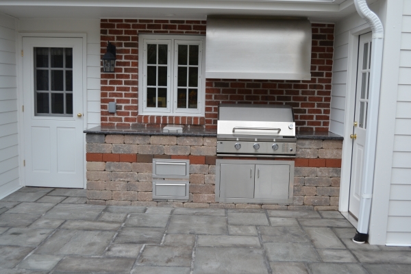 Outdoor kitchen with stainless steel grill and hood vent